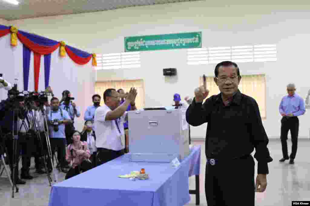 លោក ហ៊ុន សែន ប្រធានគណបក្ស​ប្រជាជន​កម្ពុជា ​លើក​ដៃចង្អុល​បង្ហាញអ្នកសារព័ត៌មាន​ បន្ទាប់​ពី​ដាក់សន្លឹក​ឆ្នោត​ចូល​ធុង នៅក្នុងមណ្ឌល​បោះឆ្នោត​ខេត្ត​កណ្តាល កាល​ពីថ្ងៃទី២៥ ខែកុម្ភៈ ឆ្នាំ​២០២៤។ (លាស់ លីបលីប/វីអូអេ) 