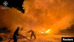 Petugas pemadam kebakaran memadamkan truk yang terbakar akibat serangan drone Rusia di kompleks pelabuhan di sungai Danube wilayah Odesa, Ukraina 26 September 2023. (Layanan pers Layanan Darurat Negara Ukraina di wilayah Odesa/Handout via REUTERS)