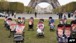 Sejumlah kereta bayi berisi foto dari para anak-anak yang disandera oleh militan Hamas ditampilkan dalam aksi demo di depan Menara Eiffel di Paris, pada 26 Oktober 2023. (Foto: AFP/Dimitar Dilkoff)