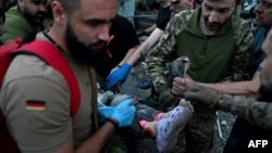 Rescuers and volunteers carry a person from the rubble created by a Russian missile attack on a restaurant and several houses in Kramatorsk, Ukraine, June 27, 2023.