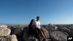 Kakak-adik Sofia Oliveira, 18 tahun, dan Andre Oliveira, 15 tahun, berfoto di pantai Costa da Caparica, di selatan Kota Lisbon, Portugal, 20 September 2023. (Foto: Ana Brigida/AP Photo)