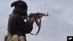 FILE - This frame grab from video posted online March 18, 2019, by the Aamaq News Agency, then a media arm of the Islamic State group, shows an IS fighter firing his weapon during clashes with U.S.-backed Syrian Democratic Forces in Baghouz, Syria.