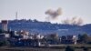 FILE - A picture taken from from the southern Lebanese village of Tayr Harfa, near the border with Israel, shows smoke from rockets fired by Hezbollah billowing near an Israeli outpost on Dec. 15, 2023. 