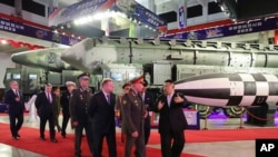 在朝鲜政府提供的这张照片中,朝鲜领导人金正恩(右)与国防部长谢尔盖·绍伊古率领的俄罗斯代表团于 2023 年 7 月 26 日在朝鲜平壤参观武器展览。