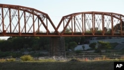 FILE - Razor wire coils underneath a railroad bridge in Eagle Pass, Texas, Sept. 9, 2023, to deter migrants using the border city as a popular crossing point into the U.S. 