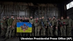 乌克兰总统泽连斯基（中）前往俄乌正在激战的巴赫穆特附近的一处阵地与乌军士兵举着军旗合影。（2023年3月22日）