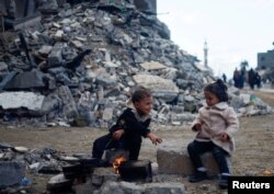 Palestinian children sit by the fire next to the rubble of a house hit in an Israeli strike during the conflict, amid a temporary truce between Hamas and Israel, in Khan Younis in the southern Gaza Strip, Nov. 27, 2023.
