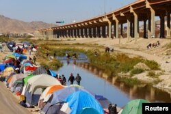 Para migran pencari suaka dari Venezuela menyeberangi sungai Rio Bravo untuk menyerahkan diri ke agen Patroli Perbatasan AS untuk meminta suaka di El Paso, Texas, AS, dekat kamp migran Venezuela, terlihat dari Ciudad Juarez, Meksiko 17 November 2022. (REUTERS /Jose Luis Gonzalez)