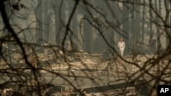 FILE - Search and rescue search through a burned out mobile home park the Camp fire, Nov. 13, 2018, in Paradise, Calif.