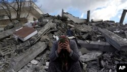 FILE - A woman sits on the rubble as emergency rescue teams search for people under the remains of destroyed buildings in Nurdagi town on the outskirts of Osmaniye city southern Turkey, on Feb. 7, 2023.