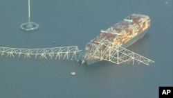 Kerangka baja jembatan Francis Scott Key di Baltimore, Maryland, tersangkut di kapal kontainer Dali, setelah salah satu penyangga jembatan itu ambruk ditabrak kapal tersebut, Selasa, 26 Maret 2024. (WJLA via AP)
