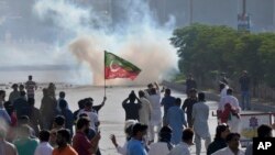 Para pendukung dari mantan Perdana Menteri Pakistan Imran Khan memblokade jalan di saat polisi menembakkan gas air mata untuk membubarkan massa dalam demo di Karachi, Pakistan, pada 9 Mei 2023. (Foto: AP/Fareed Khan)