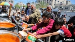 Warga Palestina mengatre untuk mendapatkan makanan yang dimasak oleh para relawan di Rafah, selatan Jalur Gaza, pada 8 Mei 2024. (Foto: Reuters/Hatem Khaled)