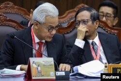 Pasangan capres/cawapres Ganjar Pranowo dan Mahfud MD berdiskusi di tengah pelaksanaan sidang gugatan hasil pilpres 2024 di Mahakamah Konstitusi, Jakarta, 27 Maret 2024. (Foto: Ajeng Dinar Ulfiana/Reuters)