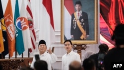 Presiden terpilih Indonesia Prabowo Subianto (Kiri) dan Wakil Presiden terpilih Gibran Rakabuming Raka (kanan) di depan potret Presiden Indonesia Joko Widodo di Kantor KPU, Jakarta, usai pengumuman pemilihan presiden 2024 di Gedung DPR, 24 April 2024. (Yasuyoshi CHIBA / AFP)