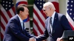 조 바이든 미국 대통령과 윤석열 한국 대통령이 26일 정상회담 후 백악관 로즈가든에서 열린 기자회견에서 악수를 나누고 있다.