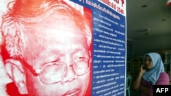 រូបឯកសារ៖ ស្ត្រីម្នាក់​ឈរ​នៅមុខ​បដា​រូប​មេធាវី Somchai Neelapaijit ដែលបាន​បាត់ខ្លួន នៅ​ខេត្ត Pattani ប្រទេស​ថៃ កាលពីថ្ងៃទី​៣០ ខែមីនា ឆ្នាំ​២០០៤។