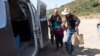 Volunteer Karen Parker, right, helps escort Arelis Alonzo Lopez, a pregnant woman from Guatemala who is seeking asylum, as she walks with a Border Patrol agent toward a van to be processed, June 5, 2024, in San Diego.