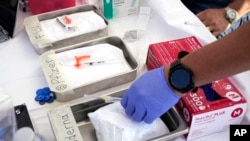 FILE - Syringes with vaccines are prepared at the L.A. Care and Blue Shield of California Promise Health Plans' Community Resource Center where they were offering members and the public free flu and COVID-19 vaccines Oct. 28, 2022, in Lynwood, Calif. 