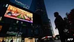 A large screen shows news coverage of Chinese President Xi Jinping, right, meeting German Chancellor Olaf Scholz in Beijing on April 16, 2024.