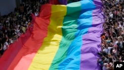 Para peserta pawai membentangkan bendera pelangi saat pawai hak-hak LGBTQ Pride Parade di Bangkok, Thailan, 4 Juni 2023. (Foto: Sakchai Lalit/AP Photo)