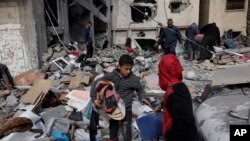 Warga Palestina berusaha menyelamatkan harta benda mereka setelah serangan udara Israel terhadap permukiman di Khan Younis, Jalur Gaza, Jumat 12 Januari 2024.