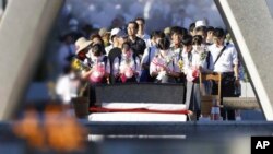 Pengunjung berdoa di depan monumen yang didedikasikan untuk para korban bom atom di Taman Peringatan Perdamaian di Hiroshima, Jepang barat, 6 Agustus 2023.