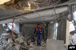 Seorang pekerja Palestina berjalan di tengah puing-puing pabrik desalinasi air yang terkena serangan di Nuseirat di Jalur Gaza tengah pada 7 Juni 2024. (Foto: AFP)