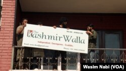 Staff at The Kashmir Walla remove the media outlet's sign from their former office in Srinagar, Indian-administered Kashmir, on Aug. 21, 2023. (Wasim Nabi/VOA)
