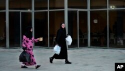 Residents displaced from her home in southern Lebanon by clashes on the border with Israel carry food March 15, 2024.