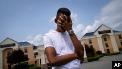 Mohamed, a 19-year-old fleeing political persecution in Mauritania, poses for a photo that obscures his face to protect his identity, outside the Crossroads Hotel, before heading into town for a work opportunity, May 22, 2023, in Newburgh, N.Y. 