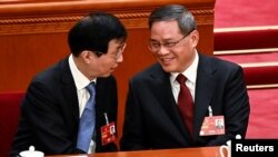 China's newly-elected Premier Li Qiang (R) is congratulated by Chinese People's Political Consultative Conference Chairman Wang Huning at the Great Hall of the People, March 11, 2023. (Greg Baker/Pool via Reuters) 