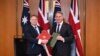 Menteri Pertahanan Inggris Grant Shapps (kiri) dan Menteri Pertahanan Australia Richard Marles bertukar dokumen Perjanjian Pertahanan dalam pertemuan di Gedung Parlemen di Canberra, 21 Maret 2024. (AAP Image/Lukas Coch via Reuters)