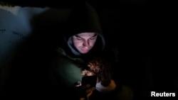 A resident and his dog take cover in a parking lot near an apartment building damaged during a Russian drone strike in Kyiv, Ukraine, Dec. 22, 2023.