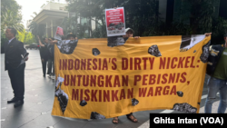 Aksi yang dilakukan oleh koalisi masyarakat sipil digelar di depan pintu masuk acara konferensi mineral kritis Indonesia 2024 yang berlangsung dari 11-13 Juni 2024 di Hotel Mulia, Senayan, Jakarta. (Foto: VOA/Ghita Intan)