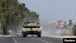 Israeli tanks drive on a road near Sderot in southern Israel, following a mass infiltration by Hamas gunmen from the Gaza Strip, Oct. 8, 2023. 