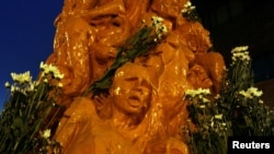 FILE - Flowers adorn on the 'Pillar of Shame — A memorial for Tiananmen' by Danish artist Jens Galschiot during a candlelight vigil at the University of Hong Kong June 3, 2009.