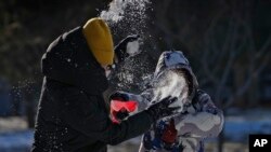 2023年12月17日，一女子在北京一座居民楼附近跟一孩子玩雪。北京在过去两个星期经历了几十年未见的低温天气。