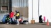FILE - Immigrants stand outside a shelter in the Pilsen neighborhood of the city of Chicago, Illinois, Dec. 19, 2023. Across Chicago, Black residents are frustrated that their long-standing needs are not being met while the needs of the city's newly arrived are met with urgency.