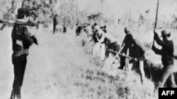 FILE - This photo taken April 16, 1976, shows people digging a water canal under the guard of an armed Khmer Rouge soldier taken in the Battambang Province, by a Cambodian who later fled and found refuge in France.