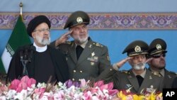 Presiden Iran Ebrahim Raisi (kiri), meninjau parade tentara memperingati Hari Angkatan Darat di depan makam mendiang pendiri revolusioner Ayatollah Khomeini di luar Teheran, 18 April 2023.