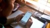 FILE - A woman uses her mobile phone to check Facebook in Naypyidaw, March 16, 2021, as Myanmar authorities ordered telecommunication companies to restrict their services on the mobile data networks, following the February 1 military coup.