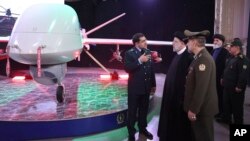 Presiden Ebrahim Raisi (2-kiri), mendengarkan Kepala Industri Penerbangan Angkatan Bersenjata Iran Jenderal Afshin Khajehfard, saat upacara peluncuran drone Mohajer-10, 22 Agustus 2023. (Foto: via AP)