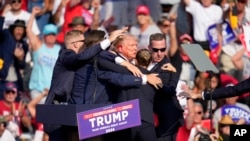Republican presidential candidate and former President Donald Trump is helped off the stage at a campaign event in Butler, Pennsylvania, July 13, 2024. 