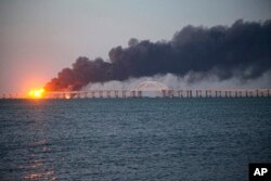 Api dan asap mengepul dari Jembatan Krimea yang menghubungkan daratan Rusia dan Semenanjung Krimea di atas Selat Kerch, di Kerch, Krimea, pada 8 Oktober 2022. (Foto: AP)