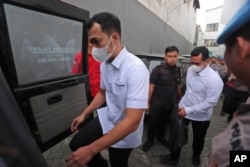 Mantan Kasat Samapta Polres Malang AKP Bambang Sidik Achmadi (kiri), dan Kabag Ops Polres Malang Kompol Wahyu Setyo Pranoto dikawal oleh satpam ke mobil kejaksaan setelah sidang vonis mereka di pengadilan negeri di Surabaya, Kamis, 16 Maret 2023. (AP/Trisnadi)