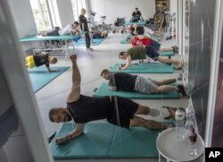 Ukrainian army veterans with amputated limbs take part in group rehabilitation exercises at the Unbroken rehabilitation center in Lviv, Ukraine, July 24, 2023.