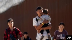 Para migran dari China berjalan setelah menyeberangi perbatasan AS-Meksiko dekat Jacumba, California, 24 Oktober 2023. (Foto: Gregory Bull/AP Photo)