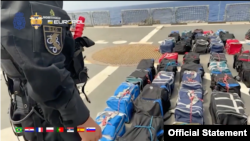 Fotografija napravljena od video snimka koji je objavio MUP Srbije 1. septembra 2023, na kojoj se vidi policajac kako stoji pored zaplenjenih putnih torbi sa kokainom, na Atlantiku.