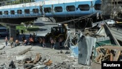 Para pekerja membersihkan lokasi yang hancur akibat serangan militer Rusia di Dnipro, Ukraina, 24 Agustus 2023. (Foto: Reuters)